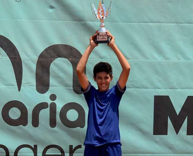 El joven jugador teldense alza el trofeo logrado como campeón alevín de Canarias/TA.